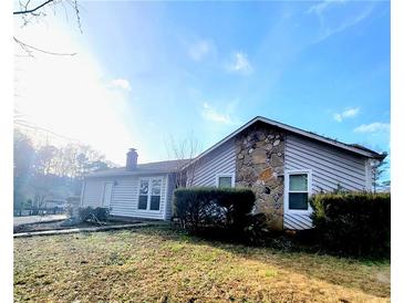 Charming home exterior features stone accents and a well-maintained front lawn under a bright sky at 4906 Kellys Mill Nw Dr, Lilburn, GA 30047