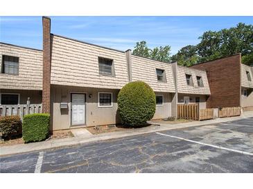 Townhouse with tan wood-look siding, chimney, trimmed bushes and small yard with parking in front at 6437 Stone Way, Morrow, GA 30260