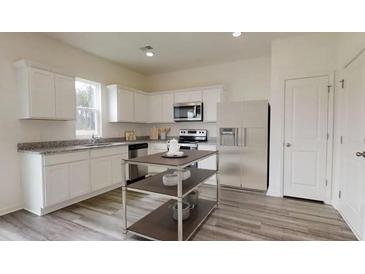 Bright kitchen with white cabinets, stainless steel appliances, and a functional island at 7728 Sudbury Cir, Covington, GA 30014