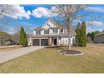 Charming two-story home featuring a stone facade, black garage doors, and well-maintained landscaping on a sunny day at 3130 Caney Creek Ln, Cumming, GA 30041