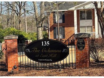 Community sign for 'The Columns at East Hill' with brick pillars and wrought iron fence, establishing a sense of place at 135 E Hill St # 24, Decatur, GA 30030