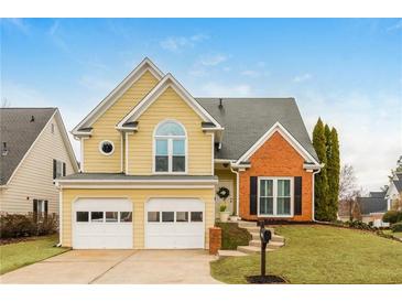 Charming yellow two-story home featuring an attached two car garage and brick accent details at 2038 Drogheda Ln, Marietta, GA 30066