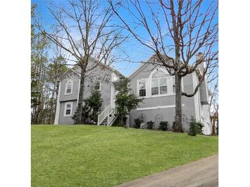 Charming two-story home with a well-manicured lawn, mature trees, and a welcoming staircase leading to the entrance at 610 Coolsprings Ln, Woodstock, GA 30188