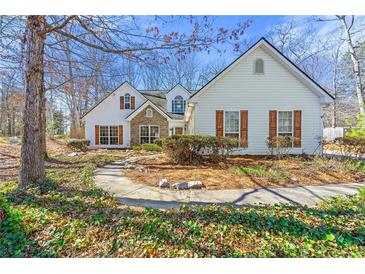 Charming home featuring stone accents, complemented by a beautifully landscaped front yard with mature trees at 4210 Hamilton Walk Dr, Buford, GA 30519