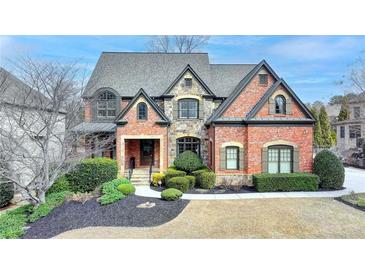 Charming brick home featuring stone accents, a well-manicured lawn, and a welcoming front entrance at 5340 Cole Creek Ln, Cumming, GA 30040