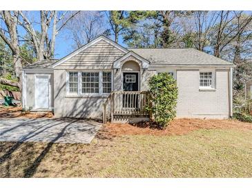 Charming single-story home featuring a painted brick facade, inviting front porch, and mature trees at 1542 Columbia Dr, Decatur, GA 30032