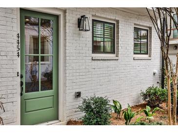 Charming home featuring a glass paned green front door, white painted brick, and modern lighting at 4454 Dandelion Ln, Atlanta, GA 30342