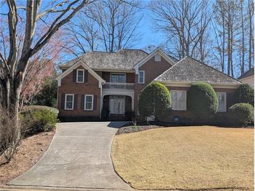 Charming brick home with a landscaped front yard and a long, curved driveway leading to the entrance at 1140 Matheson Way, Alpharetta, GA 30022