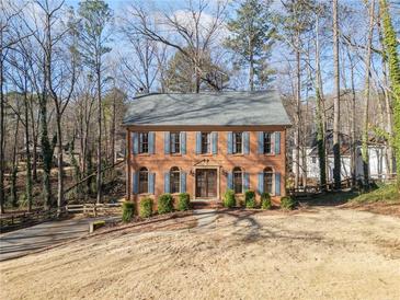 Two-story brick home with blue shutters and a spacious front lawn surrounded by trees at 505 Summer Ter, Woodstock, GA 30189