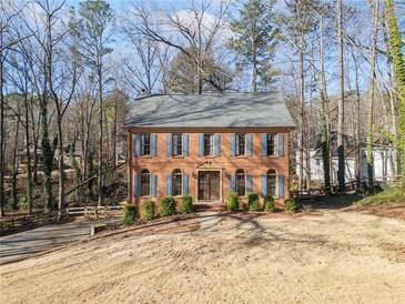 Charming brick home featuring blue shutters and a well-maintained front yard surrounded by mature trees at 505 Summer Ter, Woodstock, GA 30189