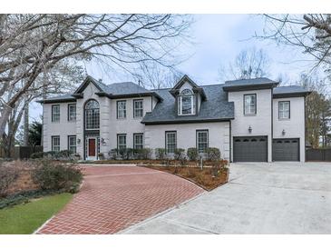 Stately brick home featuring a symmetrical facade, dormer windows, and a circular driveway at 4880 Hunters Oaks Ln, Alpharetta, GA 30009