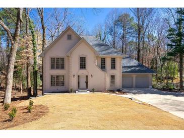 Charming two-story home featuring a three-car garage, and a well maintained lawn at 320 Woodlake Ct, Alpharetta, GA 30005