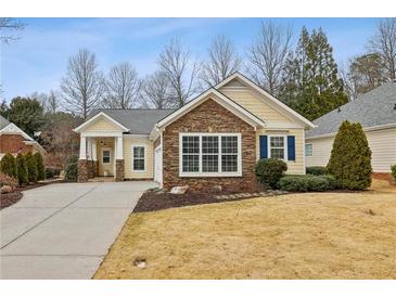 Charming yellow home with stone accents, well-manicured lawn, and paved driveway at 6775 Marlow Dr, Cumming, GA 30041