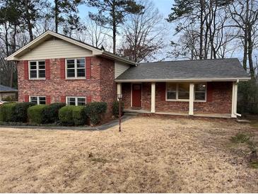 Charming brick home with a covered porch, red shutters, and mature landscaping at 951 Bingham Ln, Stone Mountain, GA 30083