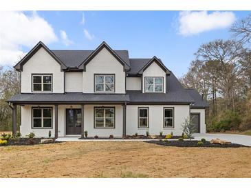 Stunning two-story home featuring white painted brick, a dark roof, and covered front porch at 1629 Phillips Rd, Lithonia, GA 30058