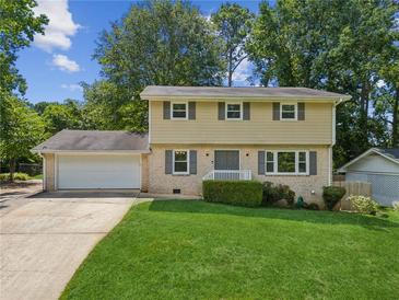 Charming two-story home with a well-manicured lawn, attached garage, and neutral color palette surrounded by mature trees at 1231 Sanden Ferry Dr, Decatur, GA 30033