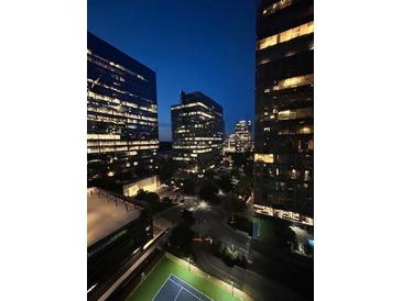 Night view of modern high-rise buildings featuring illuminated windows, city street, and a tennis court at 3445 Stratford Ne Rd # 1605, Atlanta, GA 30326