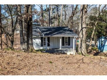 Charming single-story home with white siding, black shutters, and a cozy front porch nestled among trees at 100 Daisy Cir, Canton, GA 30114