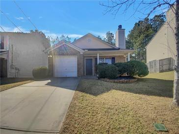 Charming single-story home with attached garage and manicured front yard landscaping at 7175 Bowie Dr, Lithonia, GA 30038