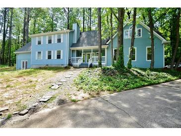 Two-story home featuring light blue siding and a welcoming front porch surrounded by lush trees at 671 Benson Hurst Sw Dr, Mableton, GA 30126
