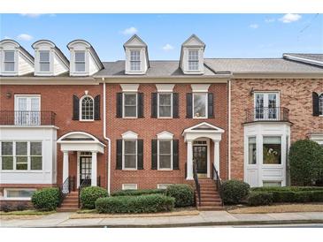 Charming brick townhome featuring dormer windows, black shutters, and manicured landscaping at 2620 Milford Ln, Alpharetta, GA 30009