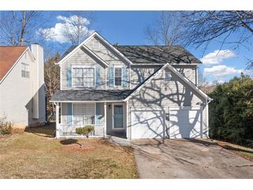Charming two-story home with a two car garage, mature trees, and a well maintained front lawn at 826 Shore Dr, Lithonia, GA 30058