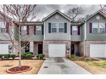 Inviting townhome exterior features gray siding, brick accents, an attached garage, and well-maintained landscaping at 1155 Magnolia Gardens Walk, Mcdonough, GA 30253