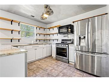 Bright kitchen featuring granite countertops, stainless steel appliances, and stylish open shelving at 1297 Quail Hunt Dr, Riverdale, GA 30296