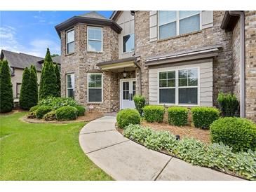 Charming brick home with lush landscaping and curved walkway leading to the covered front entrance at 2196 Abbott Dr, Buford, GA 30519