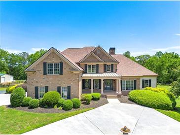Stunning brick home featuring manicured landscaping, a covered front porch, and a circular driveway with a water fountain at 714 Billings Farm Ln, Canton, GA 30115