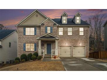 Charming two-story brick home featuring blue shutters, a two-car garage, and a cozy front porch at 5288 Clingman Ct, Douglasville, GA 30135