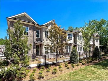 Beautiful brick townhomes featuring manicured lawns, black iron fence, and mature trees at 161 Wards Crossing Way # 121, Johns Creek, GA 30022