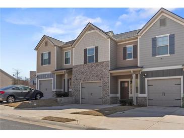 Charming townhome exterior featuring a mix of siding and brick with individual garages and well-kept landscaping at 6928 Zaniah Rd, Atlanta, GA 30331