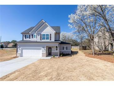 Charming two-story home with gray siding, manicured lawn, and an attached two-car garage at 7477 Caribou Trl, Riverdale, GA 30296