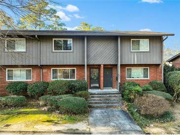 Traditional-style townhome featuring a brick and gray facade, landscaped front yard, and covered entrances at 1600 Briarcliff Ne Rd # 5, Atlanta, GA 30306