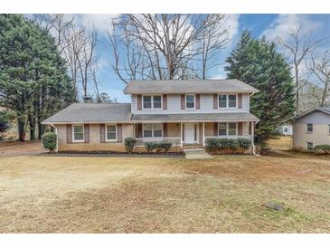 Charming two-story home with brick and siding, shutters, a covered front porch, and a well-manicured front yard at 4481 Buckingham Cir, Decatur, GA 30035