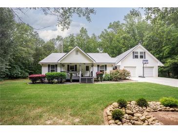 Charming home featuring a metal roof, inviting front porch, landscaping, and a two-car garage with basketball hoop at 281 Laney Dr, Locust Grove, GA 30248
