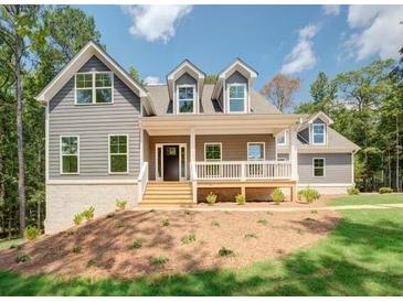 Inviting two-story home featuring a charming front porch and beautifully landscaped yard with a combination of grass and pine straw at 220 Nicklaus Cir, Social Circle, GA 30025