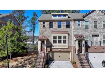 Three-story townhome with brick facade, multi-pane windows, and attached garage at 376 Provenance Dr, Atlanta, GA 30328