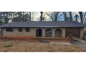 Quaint brick home featuring arched entryway and attached garage at 868 Maxey Hill Ct, Stone Mountain, GA 30083