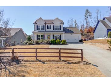 Charming two-story home featuring black shutters, an attached two-car garage and a well-manicured lawn at 4152 Woodward Mill Rd, Sugar Hill, GA 30518