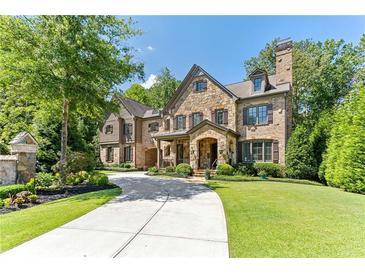 Stunning stone home with manicured lawn, circular drive, and mature trees exudes curb appeal at 200 Rivermere Way, Sandy Springs, GA 30350