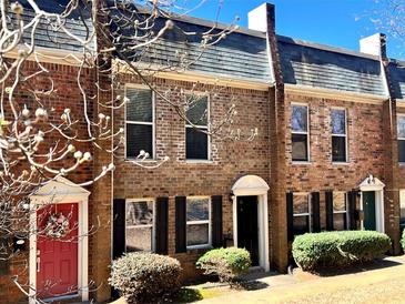 Charming brick townhouse with red door and manicured bushes in a well maintained community at 235 Winding River Dr # B, Sandy Springs, GA 30350