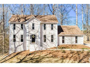 Charming two-story home featuring a stucco facade, black front door, and a well-maintained lawn at 5050 Brownwood Dr, Powder Springs, GA 30127