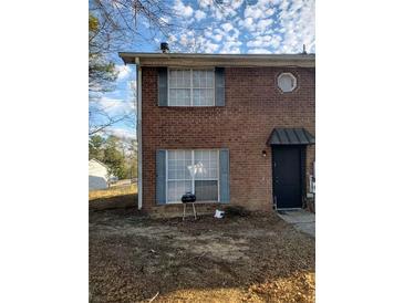 View of two-story townhouse with red brick exterior and traditional-style windows and covered entryway at 1339 Lakeview Nw Dr, Conyers, GA 30012