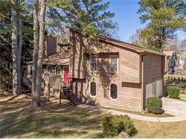 Charming multi-level home featuring a red door, beautiful wooden accents and a lush green lawn at 715 Wallington Way, Lawrenceville, GA 30046