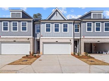 Attractive townhome with a light gray exterior, white garage doors, and coordinated landscaping for curb appeal at 1024 Rose Dr, Marietta, GA 30060