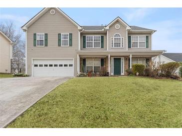 Two-story home with green shutters, covered porch, manicured lawn, and attached two-car garage at 1256 Melrose Forrest Ln, Lawrenceville, GA 30045