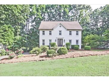 Charming two-story white brick home surrounded by lush landscaping and mature trees at 1590 Greyson Rdg, Marietta, GA 30062