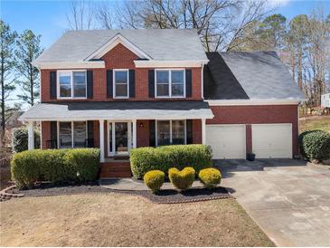 Charming brick home featuring a manicured front yard with lush green hedges and a two-car garage at 3595 Ansley Park Dr, Suwanee, GA 30024